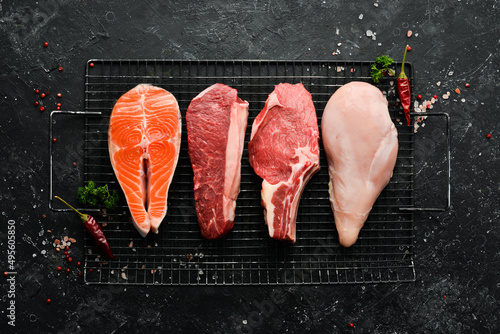 Raw food, set of steaks with salmon, veal, beef and chicken, on a dark stone background. Top view. Organic food. photo