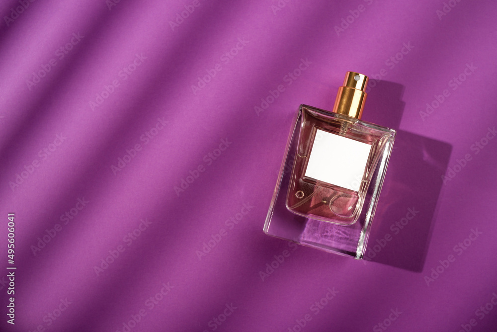 Transparent bottle of perfume on a purple background. Fragrance presentation with daylight. Trending concept in natural materials with beautiful shadows. Women's and men's essence. Transparent bottle of perfume on a purple background. Fragrance presentation with daylight. Trending concept in natural materials with beautiful shadows. Women's and men's essence.
