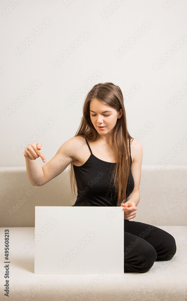 young female in black clothes holds and points to empty white board template young female in black clothes holds and points to empty white board template