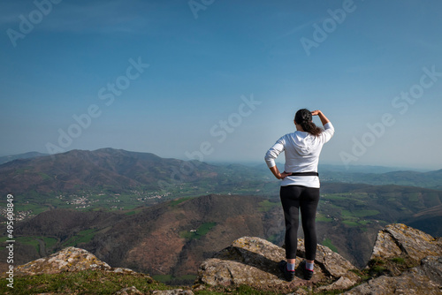 Mulher turista a apreciar as montanhas e vilas ao fundo a partir da montanha Jara em Irouléguy no País basco photo