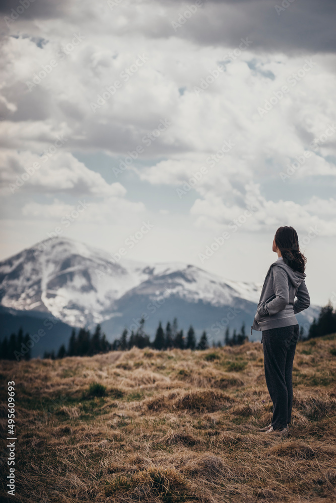 the girl stands with her back to the mountains