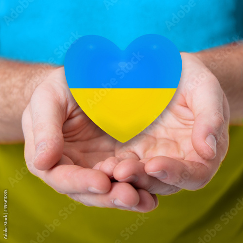 Heart mades of yellow and blue colors of National flag of Ukraine in male hands. Stop war! photo