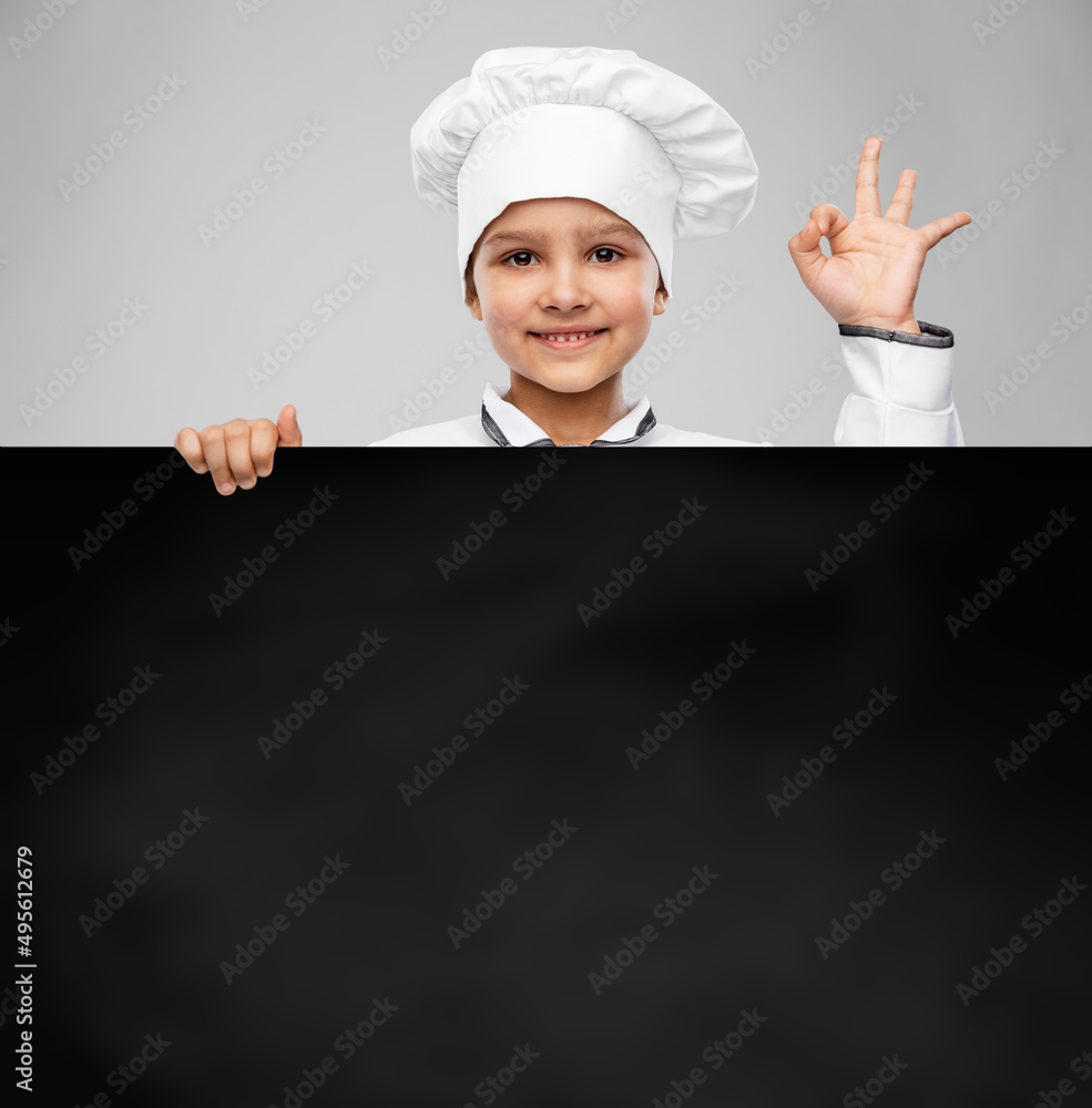 cooking, culinary and profession concept - happy smiling little girl in chef's toque and jacket with black chalkboard showing ok gesture over grey background cooking, culinary and profession concept - happy smiling little girl in chef's toque and jacket with black chalkboard showing ok gesture over grey background