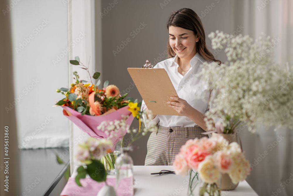 people, gardening and floral design concept - happy smiling woman or floral artist with clipboard and flowers working at studio people, gardening and floral design concept - happy smiling woman or floral artist with clipboard and flowers working at studio