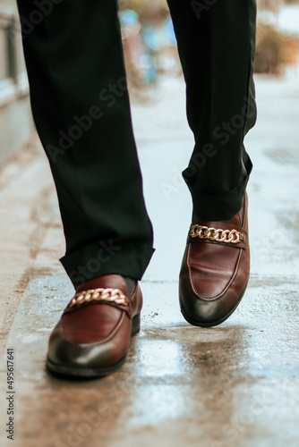 Принти на полотні Vertical shot of the lower body of a man wearing brown loafers with golden chain