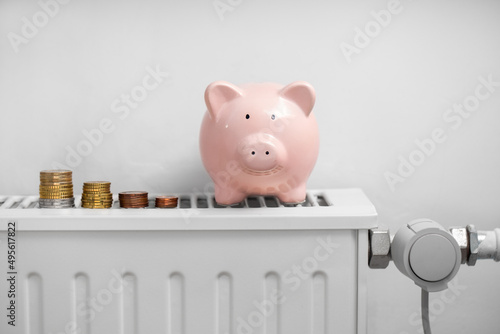 heating, energy crisis and consumption concept - piggy bank with money on radiator at home