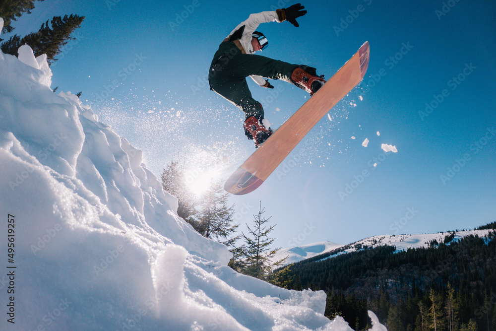 a guy jumps on a snowboard in the background of the sun and holds a front grab