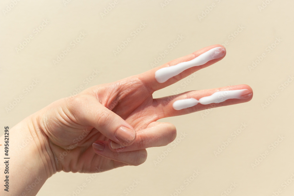 A person applying the correct amount of sunscreen for face and neck.
