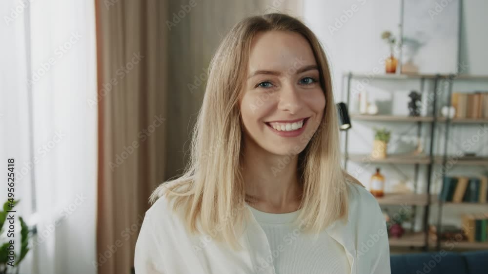 Close-up portrait of charming lady with blond hair and nude make up sitting on couch with lovely smile at home. Modern young woman with blue eyes looking directly at camera. Close-up portrait of charming lady with blond hair and nude make up sitting on couch with lovely smile at home. Modern young woman with blue eyes looking directly at camera.