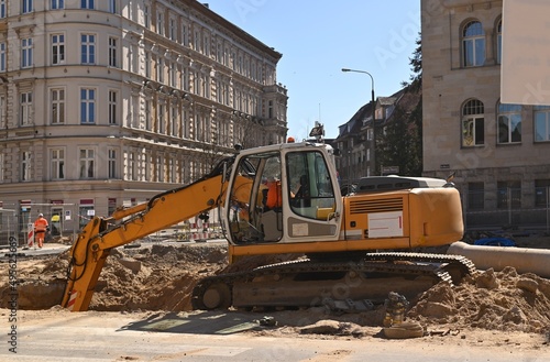 Heavy construction equipment and earthmoving excavators working on a construction site in the city. Laying or replacement of underground storm sewer pipes.