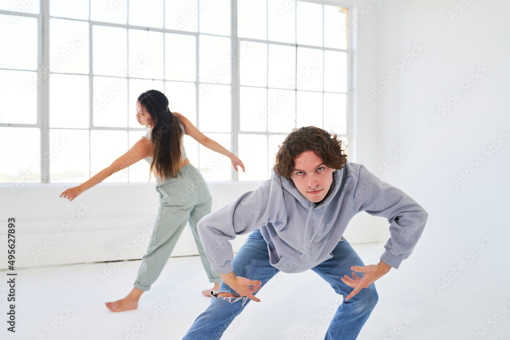 Man and woman dance and lean in front of large warehouse window