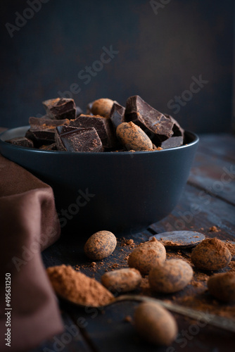 Raw choclate and choclate beans in black bowl with cocoa powder in the spoon