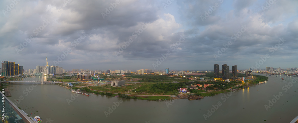Naklejka premium Aerial view of Bitexco Tower, buildings, roads, Thu Thiem 2 bridge and Saigon river in Ho Chi Minh city - Far away is Landmark 81 skyscrapper. This city is a popular tourist destination of Vietnam
