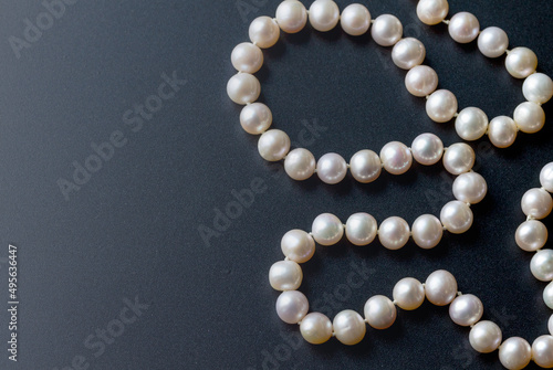 Luxury white pearl necklace on a black background with space for text