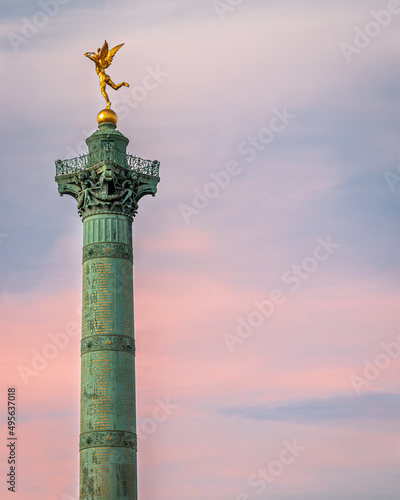 Front view of the Column of Jules in Paris while the pink sunset takes place in the background.