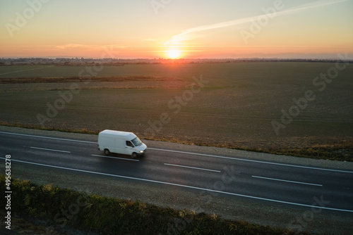 Aerial view of blurred fast moving cargo van driving on highway hauling goods. Delivery transportation and logistics concept