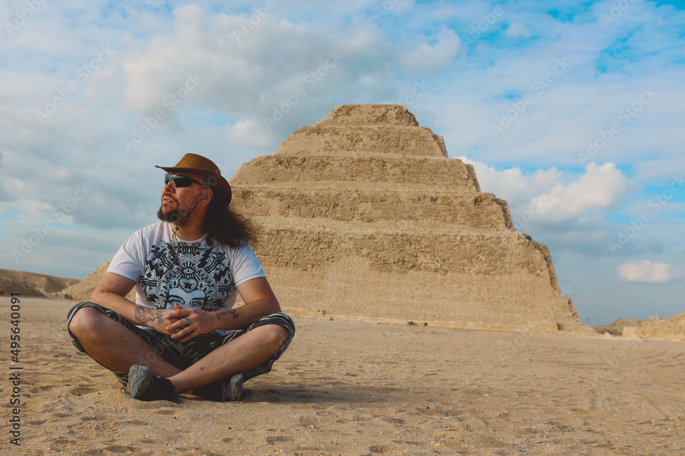 One Tourist Posing with the Step Pyramid of Djoser on the background in the Saqqara necropolis archaeological site, northwest of the city of Memphis, Egypt