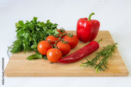 Vegetables on a wooden background, peppers and tomatoes, greens