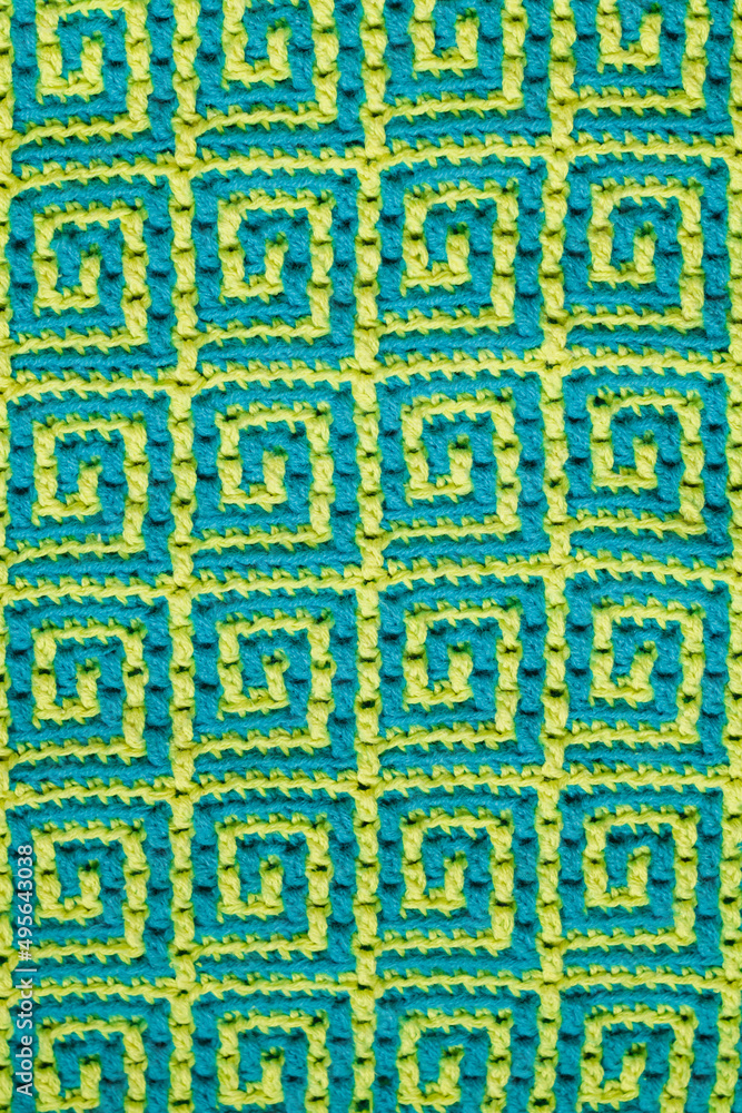 Knitted texture. Texture of jacquard fabric with yellow blue geometric ethnic pattern. Crochet mosaic pattern. Knitted texture. Texture of jacquard fabric with yellow blue geometric ethnic pattern. Crochet mosaic pattern.