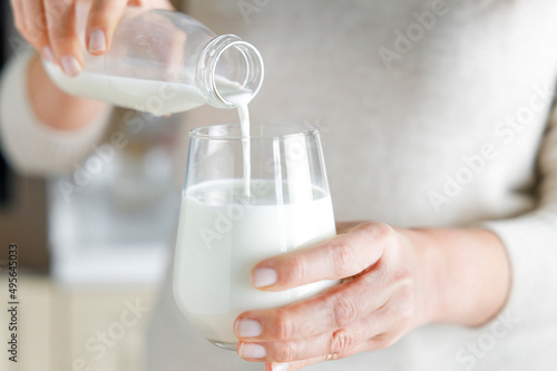 Young woman is pouring daily milk from a glass bottle