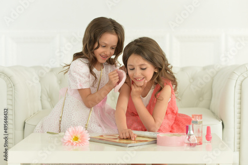 Portrait of cute sisters sitting on sofa with magazine