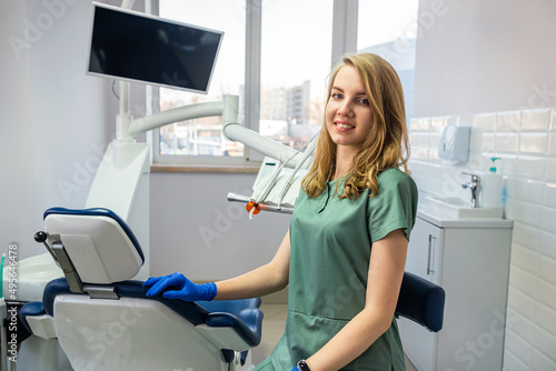Young pretty female dentist stomatology in uniform and gloves at workplace cabinet