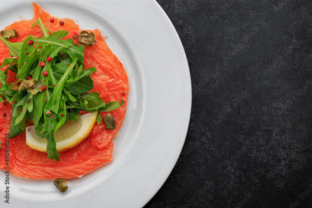 Salmon carpaccio, on a plate, with lemon , on concrete Salmon carpaccio, on a plate, with lemon , on concrete