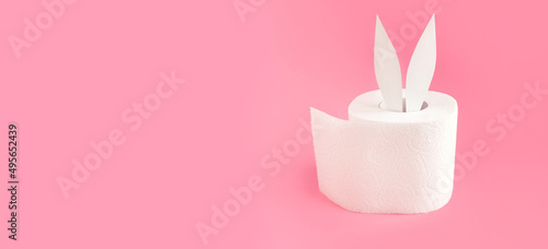 Bunny ears out of white toilet paper roll on pastel pink background. Easter coronavirus trendy rabbit concept. Side view  place for text  banner