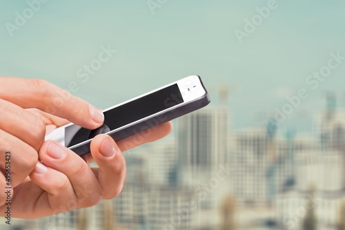 Human holds a smart phone in front of the city.