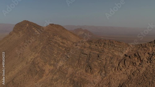 Rocky mountains top with Draa valley in background, Morocco. Aerial circling. Sky for copy space photo