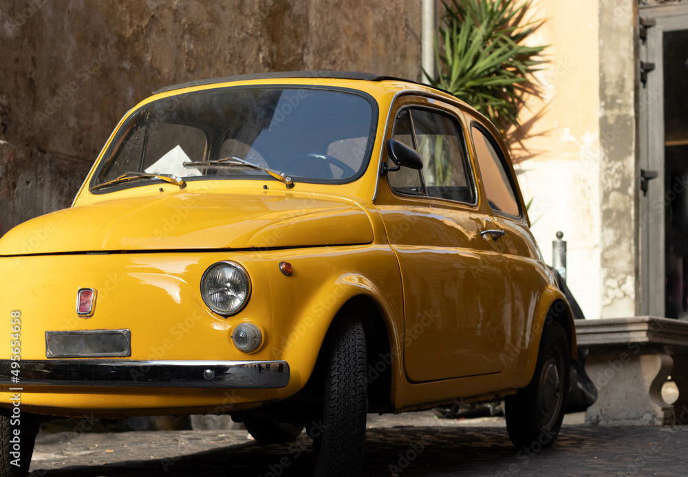 Front view of small vintage and antique yellow car in european old city streets