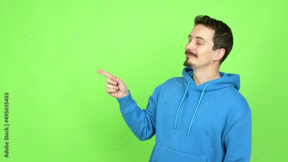 Man pointing finger to the side and presenting a product over isolated background. Green screen chroma key Man pointing finger to the side and presenting a product over isolated background. Green screen chroma key