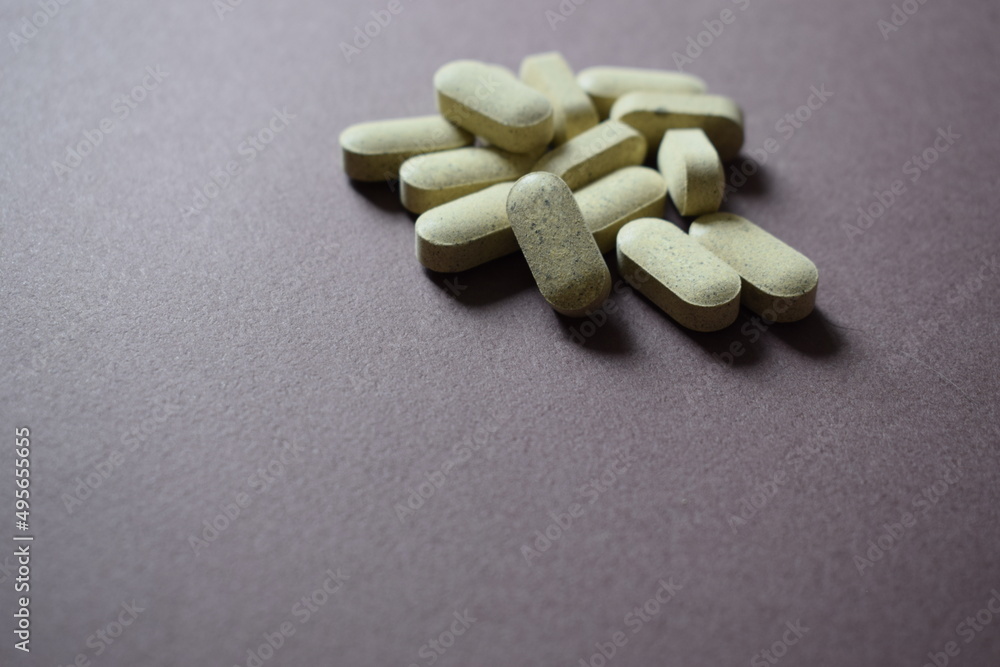 Vitamin complex on a dark purple background. Oval shaped tablets. Vitamin complex on a dark purple background. Oval shaped tablets.