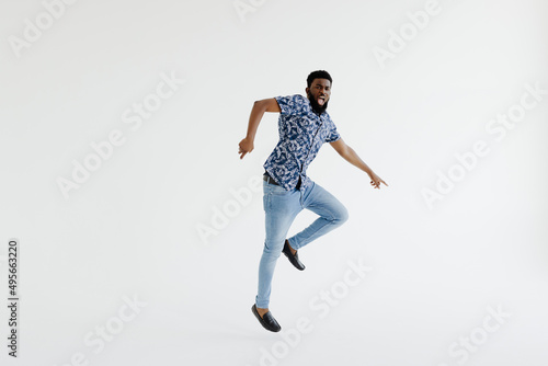 Portrait of a cheerful afro american man in headphones jumping isolated on a white background
