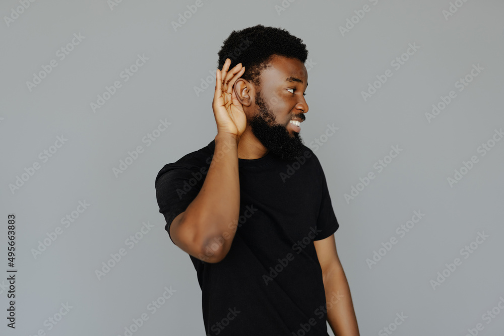 © F8  \ Suport Ukraine - Close up portrait of surprised african man holding hand near ear and trying to hear the information isolated on gray background