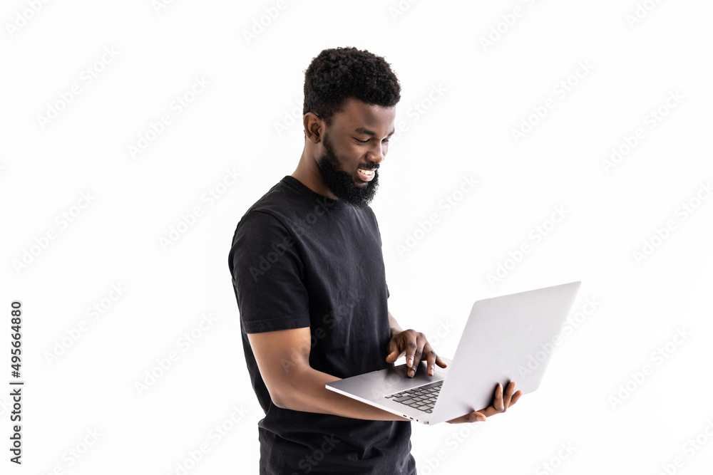 Young smiling african man standing and using laptop computer isolated over white background Young smiling african man standing and using laptop computer isolated over white background