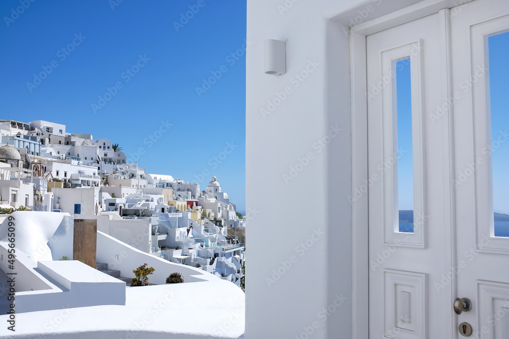 Typical design white decoration door next to an alley with a breathtaking view of the volcano and the aegean sea in Fira Santorini
