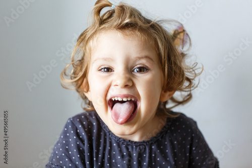 Cheerful smile child. Girl laughs close-up of the face on a white background. little girl show tongue, throat. portrait with wide open mouth and protruding tongue. clear view pulls out long tongue.