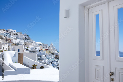 Typical design white decoration door next to an alley with a breathtaking view of the volcano and the aegean sea in Fira Santorini 