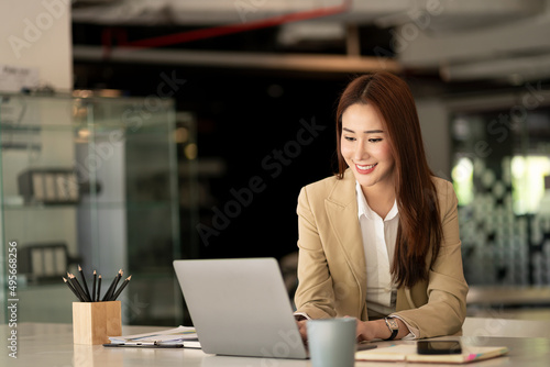 Asian businesswoman working with tiger skins notebooks graphs documents at modern desks using computers successful female e-commerce online marketing business accounting business concept