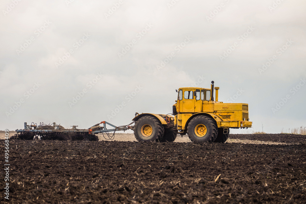 Wheeled tractor pulls the disc harrow. Side view. Wheeled tractor pulls the disc harrow. Side view.