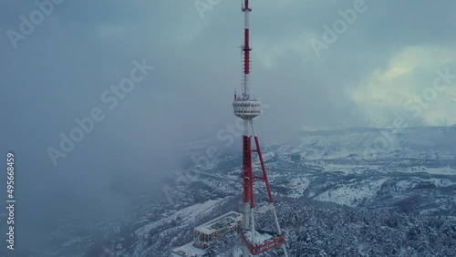 Transmit mast in the clouds above the snowy city