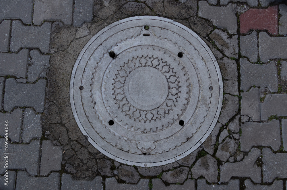 White sewer manhole on street.
