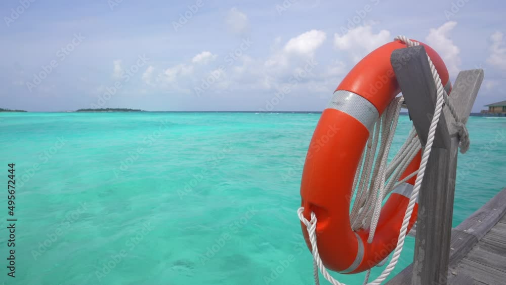 Safety equipment, Life buoy or rescue buoy in paradise island. Blue water and and cloudy sky. Tool to rescue people from drowning human. Windy day Safety equipment, Life buoy or rescue buoy in paradise island. Blue water and and cloudy sky. Tool to rescue people from drowning human. Windy day