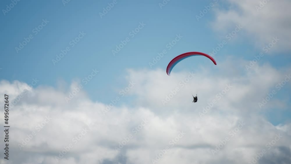 Parachutist gliding against blue sky and white clouds background. Slow motion. Extreme sports activities concept. Parachutist gliding against blue sky and white clouds background. Slow motion. Extreme sports activities concept.
