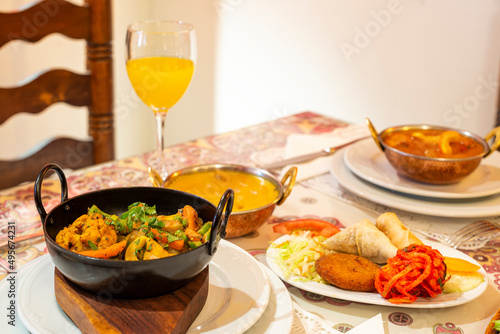 Curry stews and typical appetizers of Indian food in Europe  onion bhaji  cheese roll  samosas  falafel and pickled vegetables on the table in a restaurant