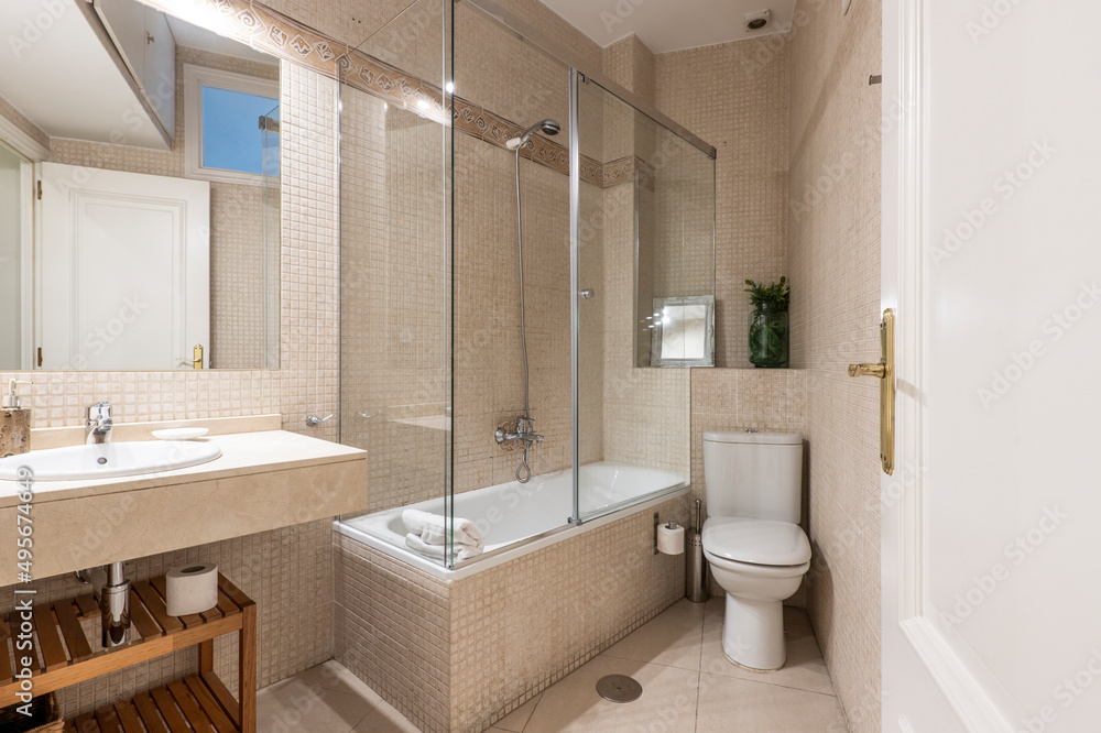 Bathroom with white porcelain sink on cream marble top, frameless mirror and shower stall with sliding glass door Bathroom with white porcelain sink on cream marble top, frameless mirror and shower stall with sliding glass door