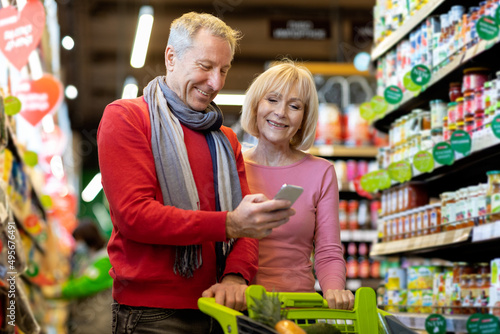 Smiling customers senior couple doing grocery in supermarket