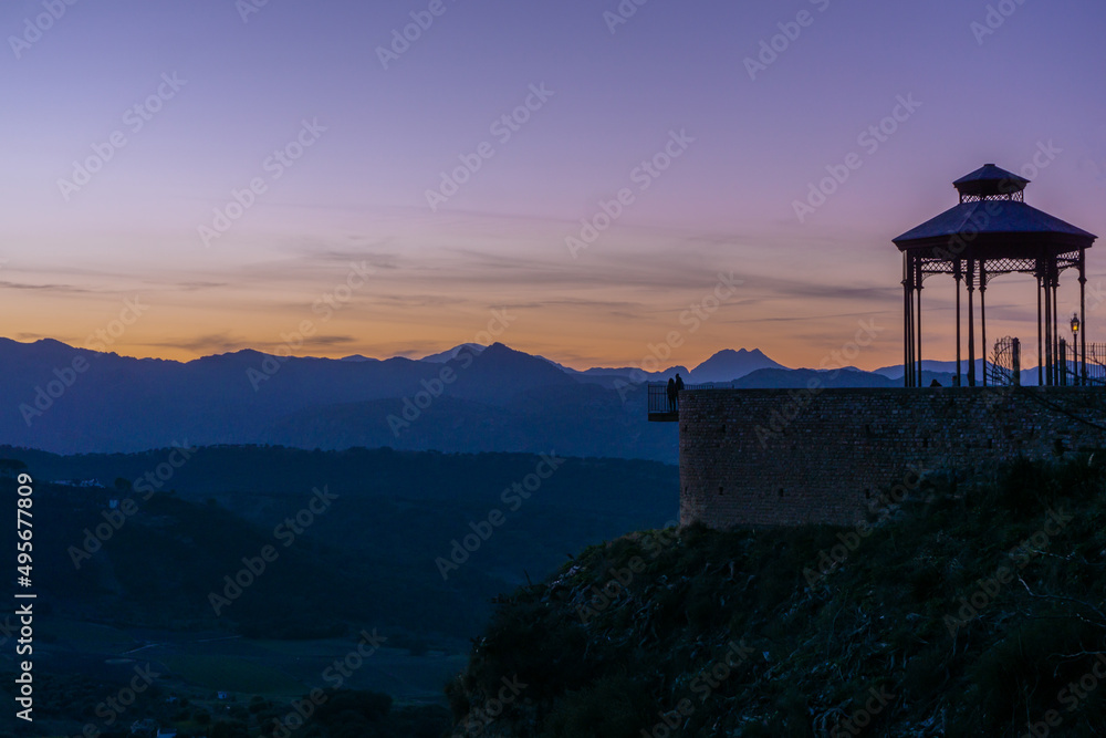 The shadow of a Couple watching the sunset behind the mountains in Ronda viewpoint, Málaga Region, Andalusia. The shadow of a Couple watching the sunset behind the mountains in Ronda viewpoint, Málaga Region, Andalusia.