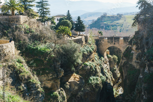 Tourist staring at the view of the Old bridge of Ronda and the Cuenca Gardens.